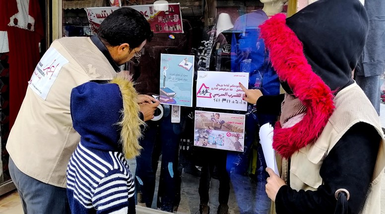 توزيع بروشورات التوعية والملصقات في الأماكن العامة والأسواق في بلدة المنصورة
